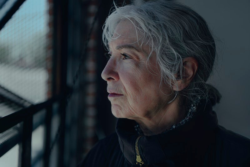 elderly woman looking through the window in a cold winter day