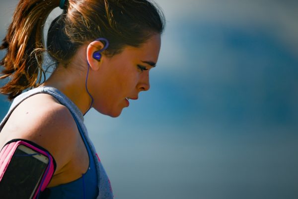 woman wearing smartphone armband and blue earphones